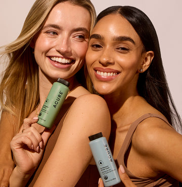 Two women with shinny and healthy hair holding a bottle of Dry Shampoo